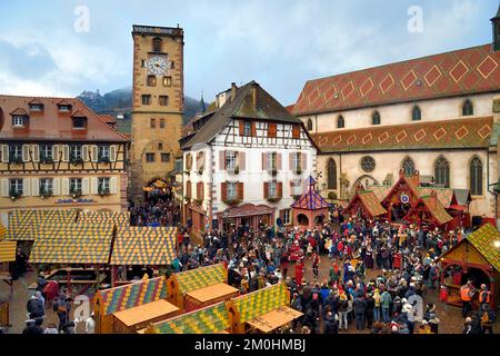 Francia, Alto Reno, Strasburgo, Ribeauvill?, il mercatino medievale di natale, balli medievali dei membri della danserie des Ribeaupierre e sullo sfondo una stalla che offre cinghiale sullo spiedo sulla piazza di fronte alla chiesa del convento agostiniano e il Tour des Bouchers (Torre dei macellai) Foto Stock