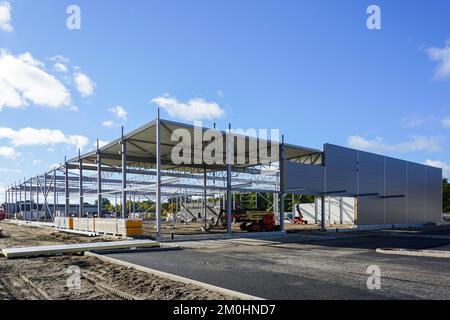 Struttura in acciaio non finita con parete a pannelli sandwich parzialmente assemblata e copertura di pannelli di copertura in metallo ondulato, nuova costruzione incompleta del magazzino Foto Stock