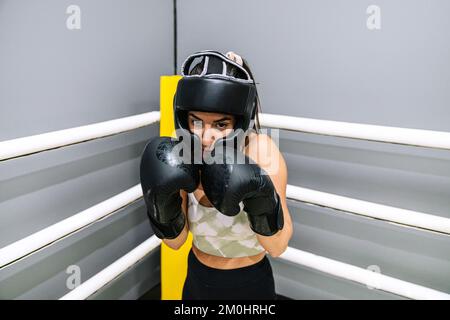 Giovane donna boxer che rimane in posizione di guardia nel ring di boxe Foto Stock