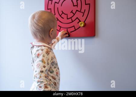 tryint grazioso del bambino per trovare un giusto senso nel giocattolo logico. Foto Stock