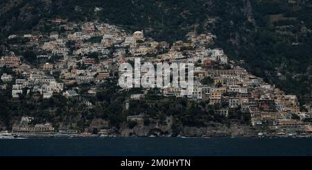 Le case colorate, i negozi e gli alberghi di Positano si stratificano verticalmente sulle scogliere d'Italia. Immagine ripresa da fuori al mare guardando verso la costa. Foto Stock