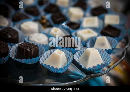 Praline di cioccolato bianco e scuro assortite disposte su un piatto di vetro Foto Stock