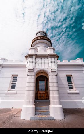 Un'inquadratura ad angolo basso di un bell'edificio del faro di Cape Byron contro un cielo nuvoloso e blu Foto Stock