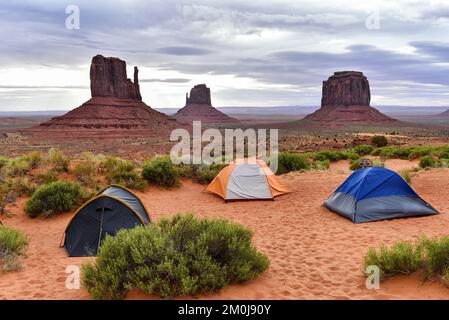 Vista sulla famosa Monument Valley dal campeggio con tre tende in primo piano. Vista di West Mitten Butte, East Mitten Butte e Merrick Butte i. Foto Stock