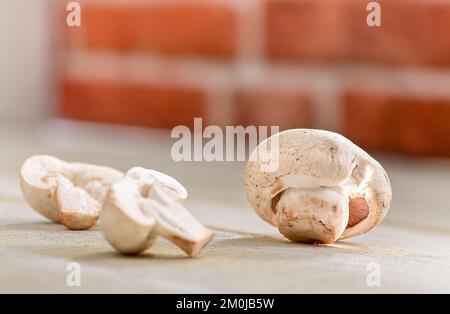 Affettato ​​mushrooms su un tavolo di legno bianco in cucina. Foto Stock