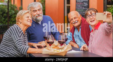 Gli anziani prendono un selfie al tavolo - la coppia matura si diverte al ristorante - concetto Senior Foto Stock