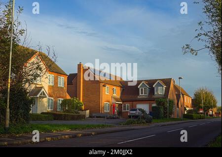 Moderne case di lusso lungo una strada suburbana in una soleggiata giornata autunnale Foto Stock