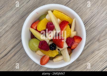 Vista dall'alto di un generoso recipiente di frutta fresca a fette, tra cui fragola, pera e arancia. Foto Stock