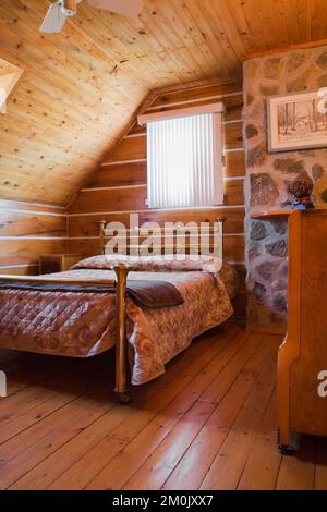 Antico letto in ottone e comò nella camera da letto al piano superiore all'interno del 1978 ha costruito una replica della vecchia casa in legno decorata in stile cottage canadese del 1800. Foto Stock