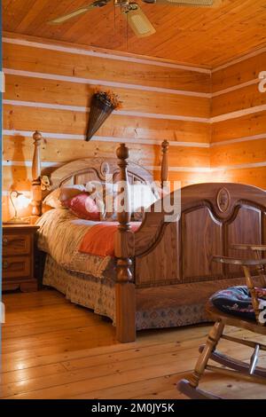 Antico letto a baldacchino in legno e tavolo da notte in camera da letto all'interno 1978 costruito replica della vecchia casa in tronchi 1800s. Foto Stock