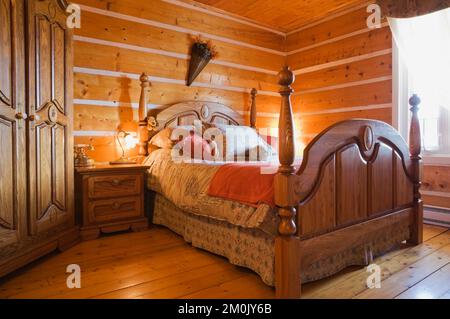 Antico letto a baldacchino in legno e tavolo da notte in camera da letto all'interno 1978 costruito replica della vecchia casa in tronchi 1800s. Foto Stock