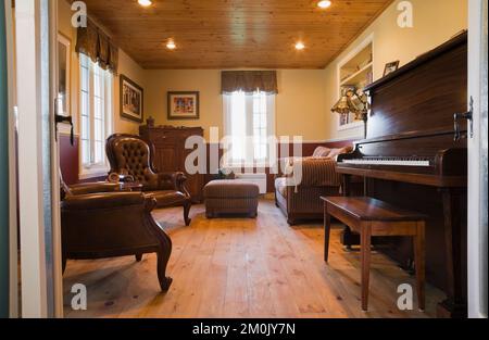 Poltrone in pelle marrone, mobili antichi nello studio e sala musica all'interno del 1978 ha costruito una replica della vecchia casa in legno e pietra di campo in stile cottage canadese. Foto Stock