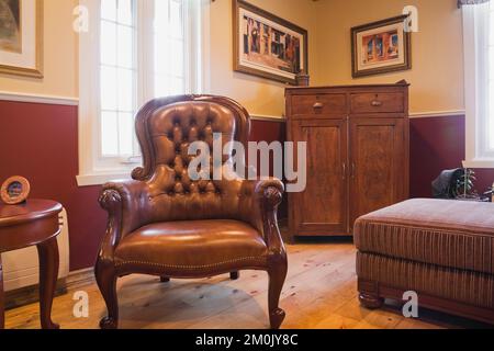 Poltrona in pelle marrone e mobili antichi in sala studio all'interno 1978 costruito replica di vecchio stile cottage log e fieldstone casa. Foto Stock