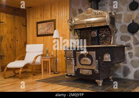 Antica stufa in ghisa in legno nel seminterrato camera familiare all'interno 1978 costruito replica di vecchio canadiana cottage stile log e fieldstone casa. Foto Stock