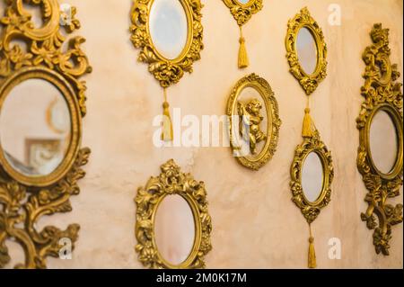Una selezione di lussuosi specchi antichi con cornici dorate e decorazioni stilizzate appese a una parete Foto Stock