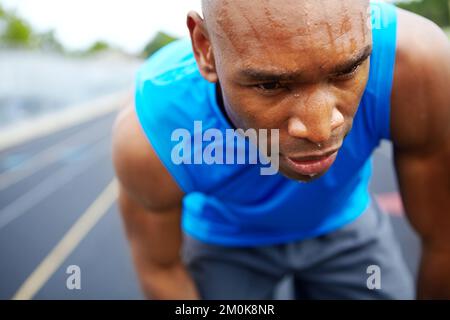 Gli diede tutto. Primo piano corto di un atleta maschio che entra nella posizione di partenza. Foto Stock