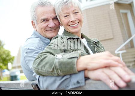 Ci sosteniamo a vicenda. Un marito maturo e una moglie che coccolano insieme su una panchina. Foto Stock