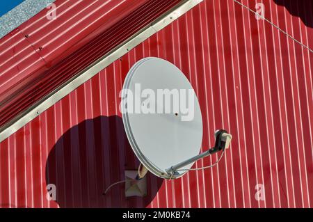Un'antenna parabolica è appesa alla parete della casa Foto Stock