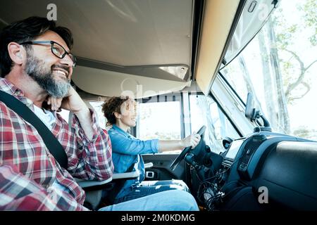 Autista donna che guida un camper con un uomo felice sul sedile del passeggero. Coppia alternativa godendo viaggio e van vacanza motorhome e lifestyl Foto Stock