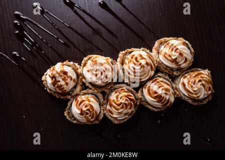 Vulcano sushi roll con formaggio cremoso in cima, vista dall'alto. Involtini caldi di tempura su fondo scuro versato con salsa. Spazio di copia Foto Stock