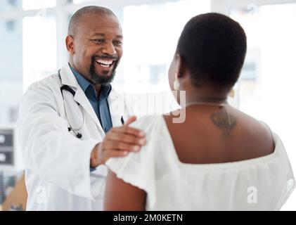 Medico allegro che offre un supporto paziente. Medico africano-americano maturo che tocca un paziente sul braccio. Buon gp che offre un comfort per il paziente in un Foto Stock