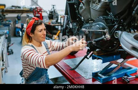 Donna meccanica che rivede moto sopra piattaforma Foto Stock