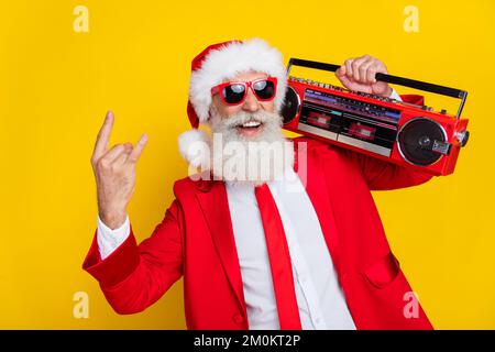 Foto di divertente claus Charming vestire rosso tux costume tux mostrando hard rock gesto ascolto boom box isolato di colore giallo sfondo Foto Stock