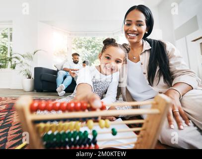 Madre ispanica seduta sul pavimento nella lunge a casa sorridendo con la figlia mentre gioca con i giocattoli educativi. Adorabile bambina che gioca Foto Stock