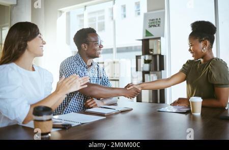Un giovane uomo d'affari felice si stringe le mani in un incontro con un collega che batte sul lavoro. Allegra donna d'affari ispanica che batte le mani per africano Foto Stock