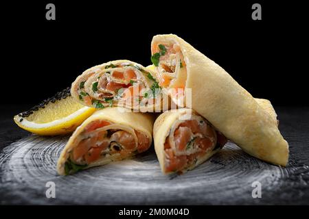 Frittelle con salmone, formaggio spalmabile ed erbe su fondo nero Foto Stock