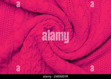 La texture del caldo maglione lavorato a maglia. Splendido motivo a maglia fatto a mano. Dimostrazione Pantone colore dell'anno 2023 viva magenta. Foto Stock