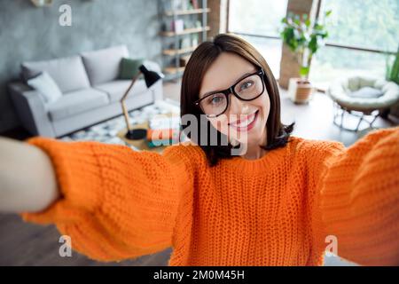 Foto di una donna allegra vestita arancione pullover eyewear registrazione video interna officina workstation Foto Stock