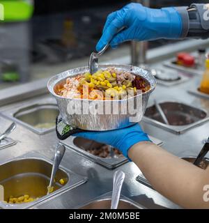 Cuocete preparando l'insalata da portare via. Foto Stock