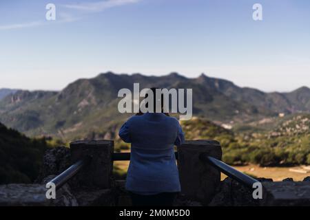 Una vista posteriore di una donna turistica che scatta foto delle montagne a Grazalema, Cadice, Andalusia Foto Stock