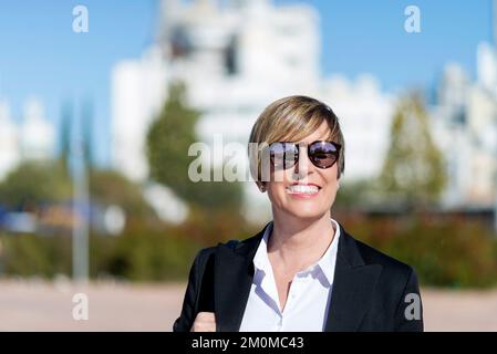 Ritratto a metà lunghezza di un sicuro e orgoglioso ceo esperto vestito con abbigliamento elegante guardando la fotocamera mentre si è in piedi per strada Foto Stock