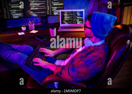 Foto di cool serio ragazzo vestiti occhiali cappello sistema di digitazione programma indoor workstation workshop casa Foto Stock