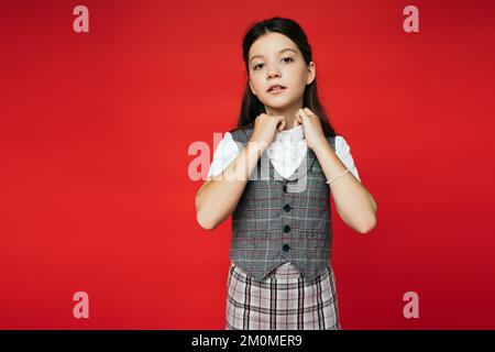 ragazza presen in giubbotto a scacchi e gonna collare di regolazione della blusa bianca isolato su rosso, banner Foto Stock