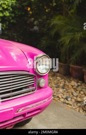 Primo piano del faro di un'auto retrò rosa, ripresa verticale Foto Stock