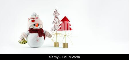 Pupazzo di neve carino fatto a mano con campane di jingle e alberi di Natale creativi su bastoni di legno con sfondo bianco Foto Stock