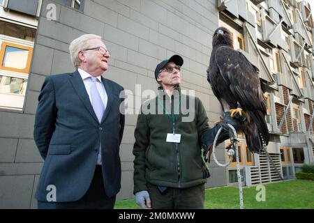 Edimburgo, Scozia, Regno Unito. 7 dicembre 2022. NELLA FOTO: (L-R) Jackson Carlaw MSP, Barry Blyther, Stanley The Golden Eagle. La commissione per la partecipazione dei cittadini e le petizioni pubbliche prenderà le prove del firmatario prima della giornata per comprendere meglio l'impatto della legislazione del 2020 sulla falconeria in Scozia e se vi sono state conseguenze involontarie. Il petitioner Barry Blyther, Roxanne Blyther e Stanley l'aquila d'oro. Il Comitato dovrà inoltre prendere atto del Ministro dell'ambiente, della biodiversità e della riforma fondiaria e di NatureScot il 21st dicembre 2022. Credito Foto Stock
