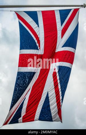 Bandiera britannica su un palo che galleggia nel vento Foto Stock