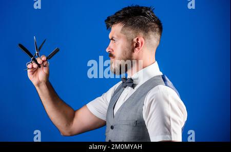 Consigli per la cura della barba. Gilet uomo con cravatta di prua tenere diritto rasoio sfondo blu. Barbiere concetto d'arte vintage. Barbiere orriolante con affilato Foto Stock