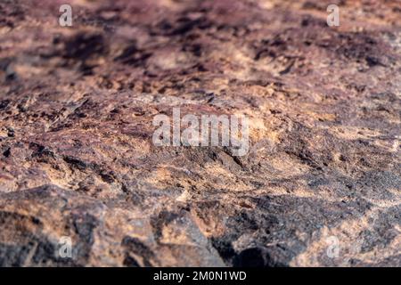 Superficie colorata di pietra mineralizzata. Cratere di Ramon. Deserto del Negev. Israele. Messa a fuoco selettiva Foto Stock