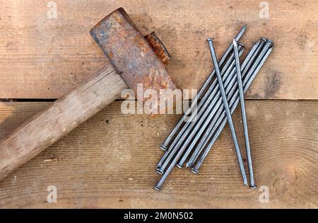 Vantage vecchio martello arrugginito e chiodi giacenti su tavole di legno. Vista dall'alto Foto Stock