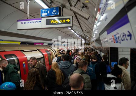 Affollata stazione della metropolitana di Londra, passeggeri su piattaforma e treno. La stazione della metropolitana di Tottenham Court Road è affollata di passeggeri a Natale Foto Stock