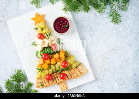 Piatto di formaggi natalizi a forma di albero di Natale servito con cracker e salsa di mirtilli rossi. Spazio di copia della vista superiore Foto Stock