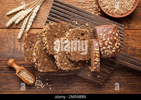 Pane integrale di segale a grani con semi tagliati a fette di pane su tavola di legno, vista dall'alto Foto Stock