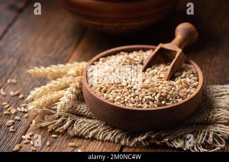 Grano intero, farro grani in una ciotola di legno. Concetto di agricoltura, raccolto di cibo Foto Stock