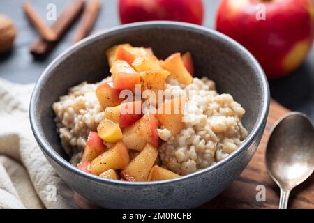Ciotola di farina d'avena per torta di Sana colazione vegana con avena cotta con mele saltate e cannella Foto Stock