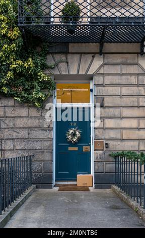 Casa georgiana porta di fronte con la corona di Natale e il pacco consegnato incustodito a casa, Edinburgh New Town, Scozia, Regno Unito Foto Stock